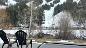 A deck with two Adirondack chairs and a hot tub overlooking a snowy mountain landscape. - Mountain Side luxury Condo (Ketchum)