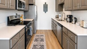 Une cuisine moderne dotée d’appareils électroménagers en acier inoxydable, de meubles en bois et d’une pancarte d’accueil.