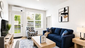 Un salon moderne avec un canapé, un fauteuil, une table basse et un téléviseur.