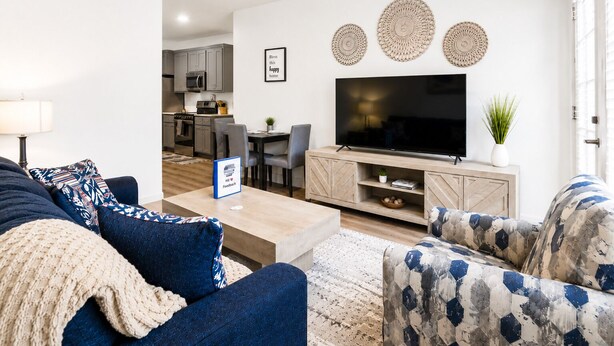 Un salon moderne avec un canapé, une table basse et un meuble pour la télévision. Il y a également un coin repas avec une table et des chaises.