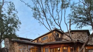 A rustic stone house with a stone foundation, wooden exterior, and large windows.