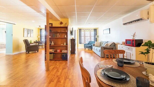 Uma sala de estar ampla com uma mesa de jantar de madeira, uma estante e um sofá.