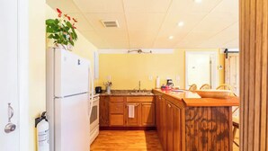 Cozinha compacta com armários de madeira, geladeira branca e bancada de madeira.