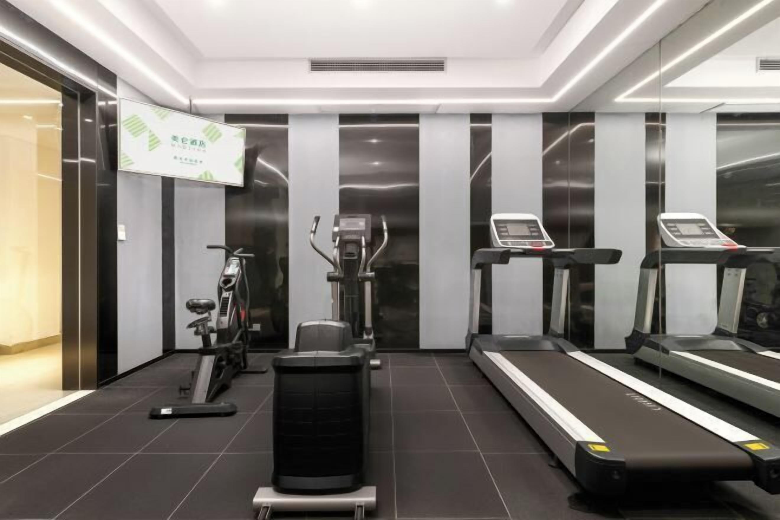 A modern gym with exercise equipment including treadmills, an elliptical, and weight machines.