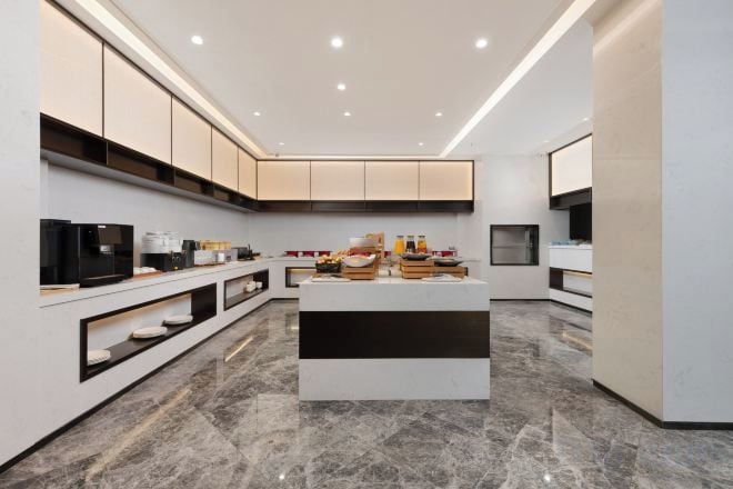 A modern kitchen with a central island, built-in appliances, and a marble floor.