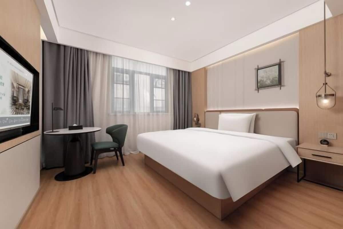 Quarto de hotel moderno com uma cama grande, uma escrivaninha e uma cadeira.