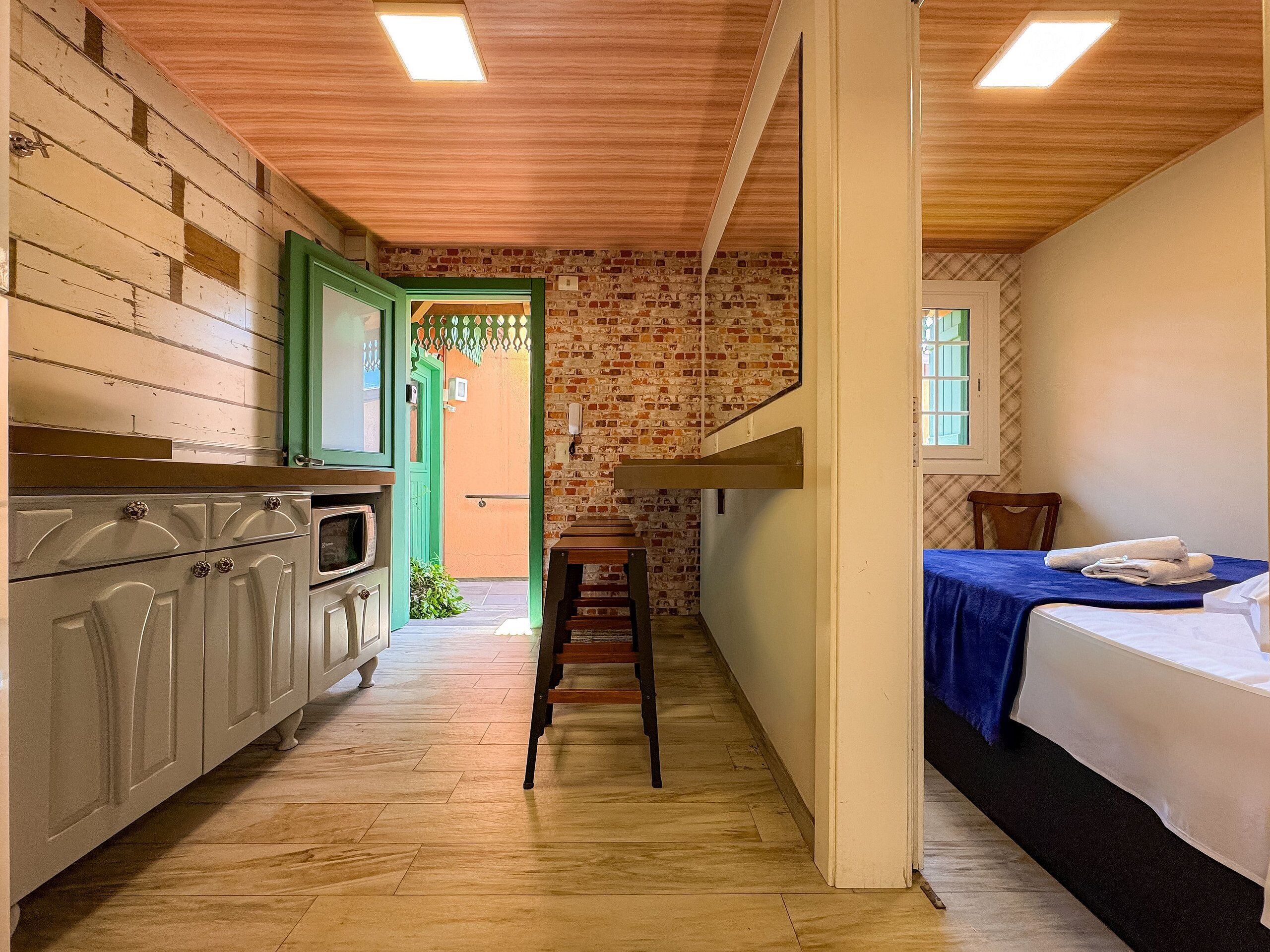 Un pasillo estrecho con una cocina a un lado, una escalera y una cama al otro.