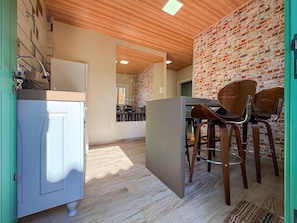 A kitchen with a wooden ceiling, a brick wall, and a dining area with wooden chairs. - Bella Serra Gramado Residence (Gramado)