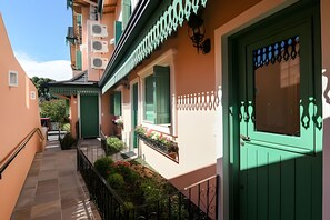 A building with a green door, a balcony with plants, and a staircase.
