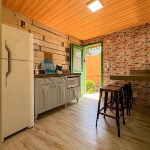 A kitchen with a refrigerator, cabinets, and a dining area with chairs. - Bella Serra Gramado Residence (Gramado)