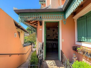 A narrow alleyway leading to a building with a green awning and a visible kitchen area.