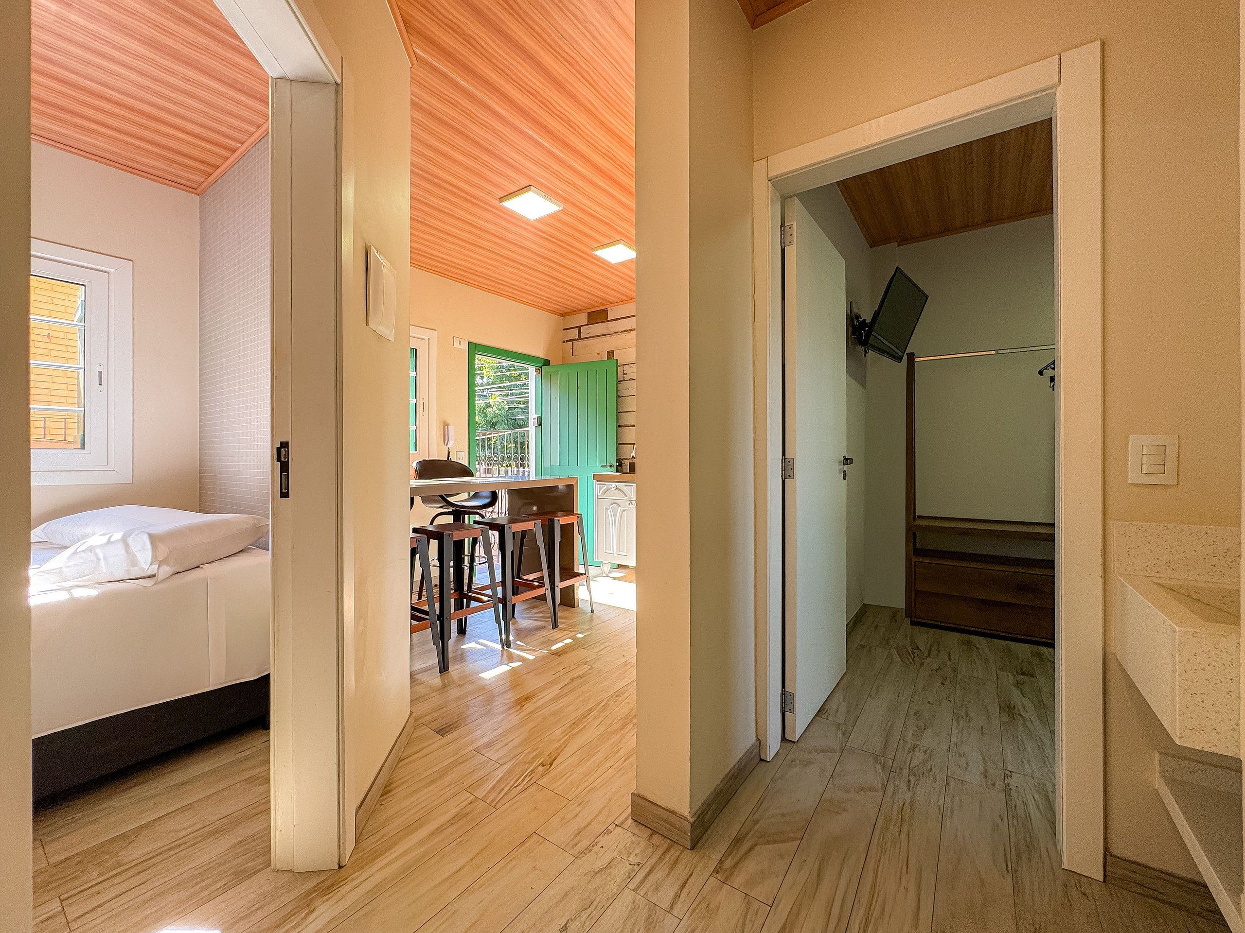 Um quarto com cama, uma mesa de jantar com cadeiras, uma área de cozinha e uma escada.