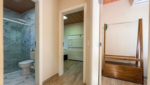 A hallway with a bathroom on the left, a wooden shelf on the right, and a bedroom in the background. - Bella Serra Gramado Residence (Gramado)