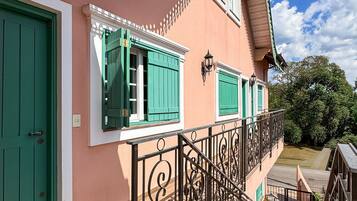 A building with a staircase, green shutters, and a balcony.