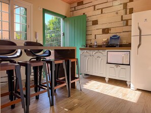 A kitchen with a white refrigerator, a sink, and a window with a view of greenery.