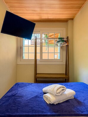 A room with a bunk bed, a window with a view, and a TV mounted on the wall.