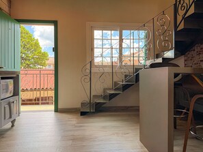 A staircase with ornate metal railings, a wooden floor, and a view of the outside through a door.