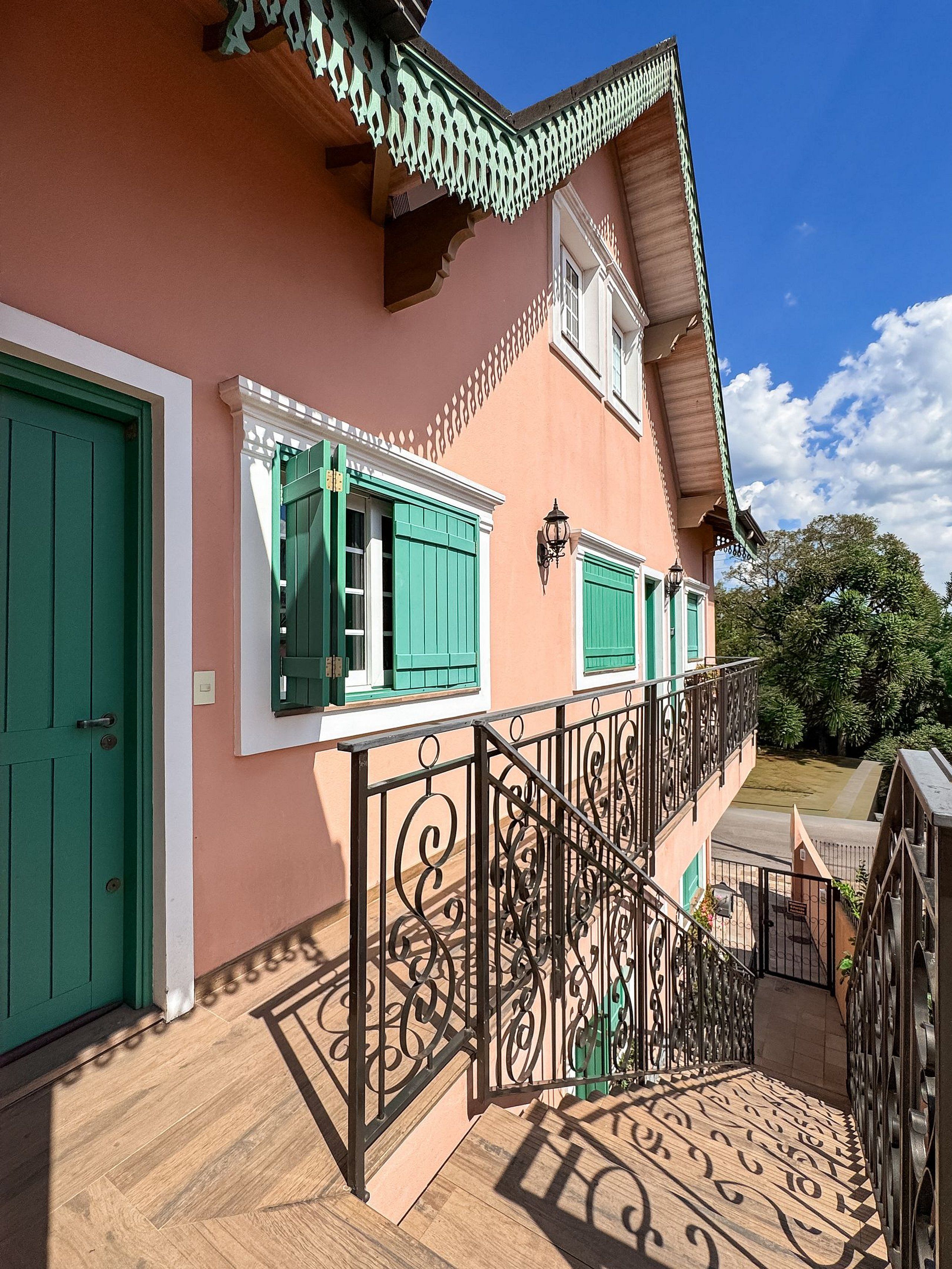 Un edificio con escaleras, contraventanas verdes y un balcón.
