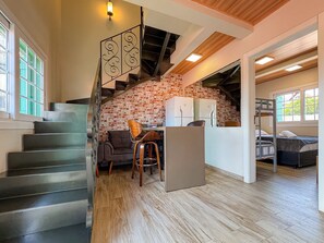 A modern interior with a staircase, a brick wall, a wooden ceiling, and a kitchenette area. - Bella Serra Gramado Residence (Gramado)