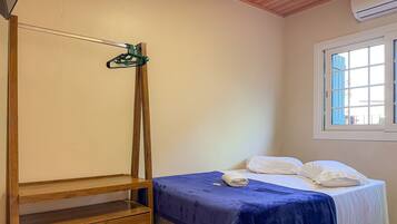 Un dormitorio con cama, armario de madera, ventana y lámpara colgante.