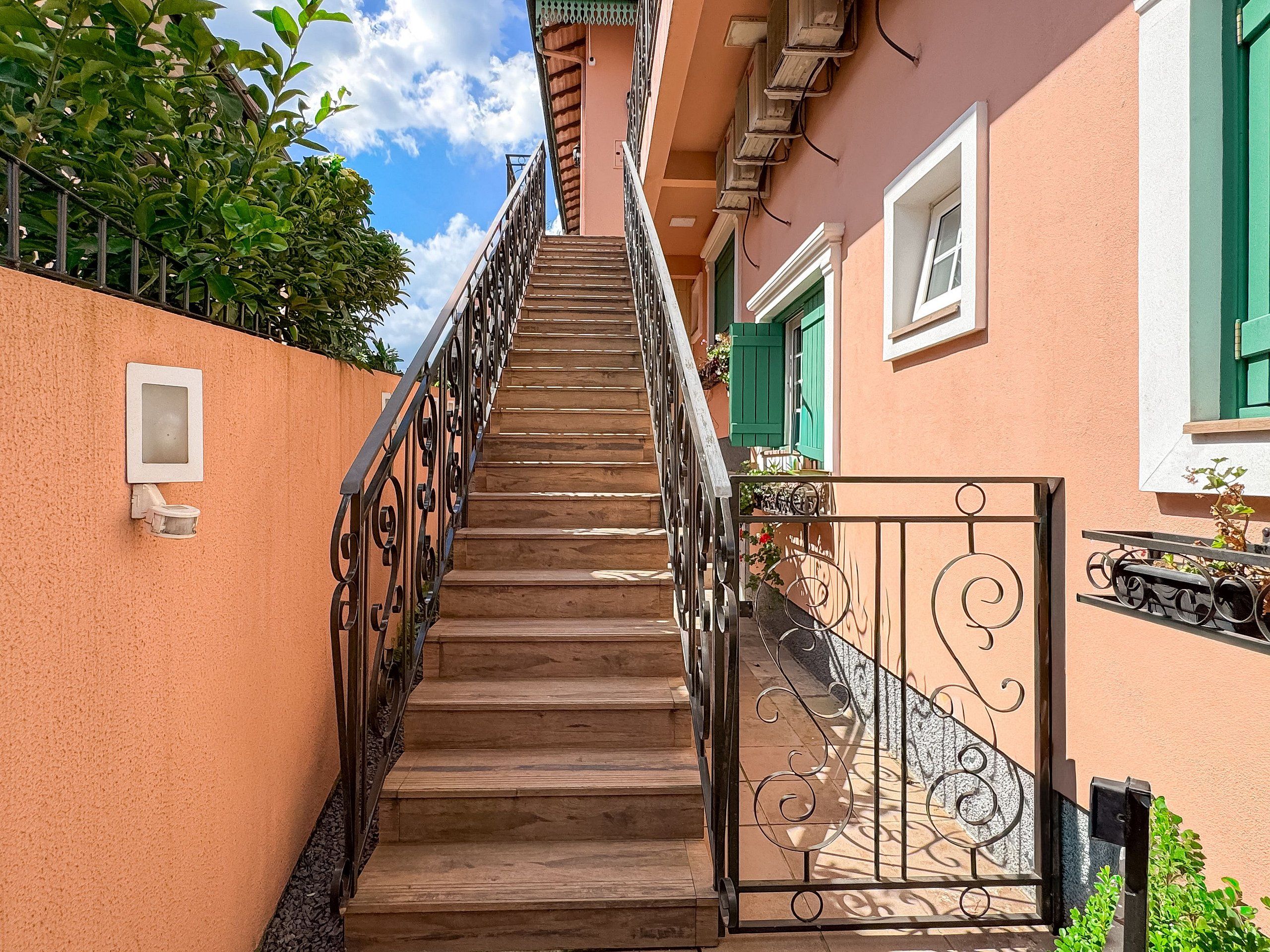 A staircase leading to a building with a metal gate and a small window.