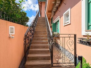 Eine Treppe führt zu einem Gebäude mit einem Metallgitter und einem kleinen Fenster.