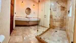 A bathroom with a glass-enclosed shower, a marble sink, and a mirror. - Hotel Suites Piamonte (Bernal)