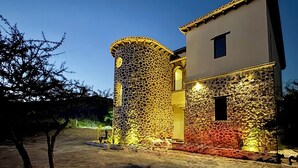A building with a stone facade and a modern design, featuring a cylindrical tower and a flat-roofed section. - Hotel Suites Piamonte (Bernal)