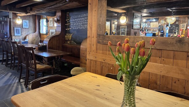 A wooden interior with a table, chairs, and a vase of tulips. - The Ship Inn (Mevagissey)