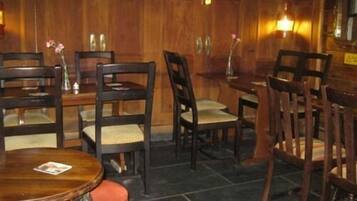 A restaurant interior with wooden paneling, multiple tables and chairs, and a tiled floor.