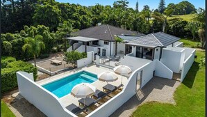 Ein modernes Haus mit Pool, Sitzgelegenheit im Freien und einem gepflegten Garten.