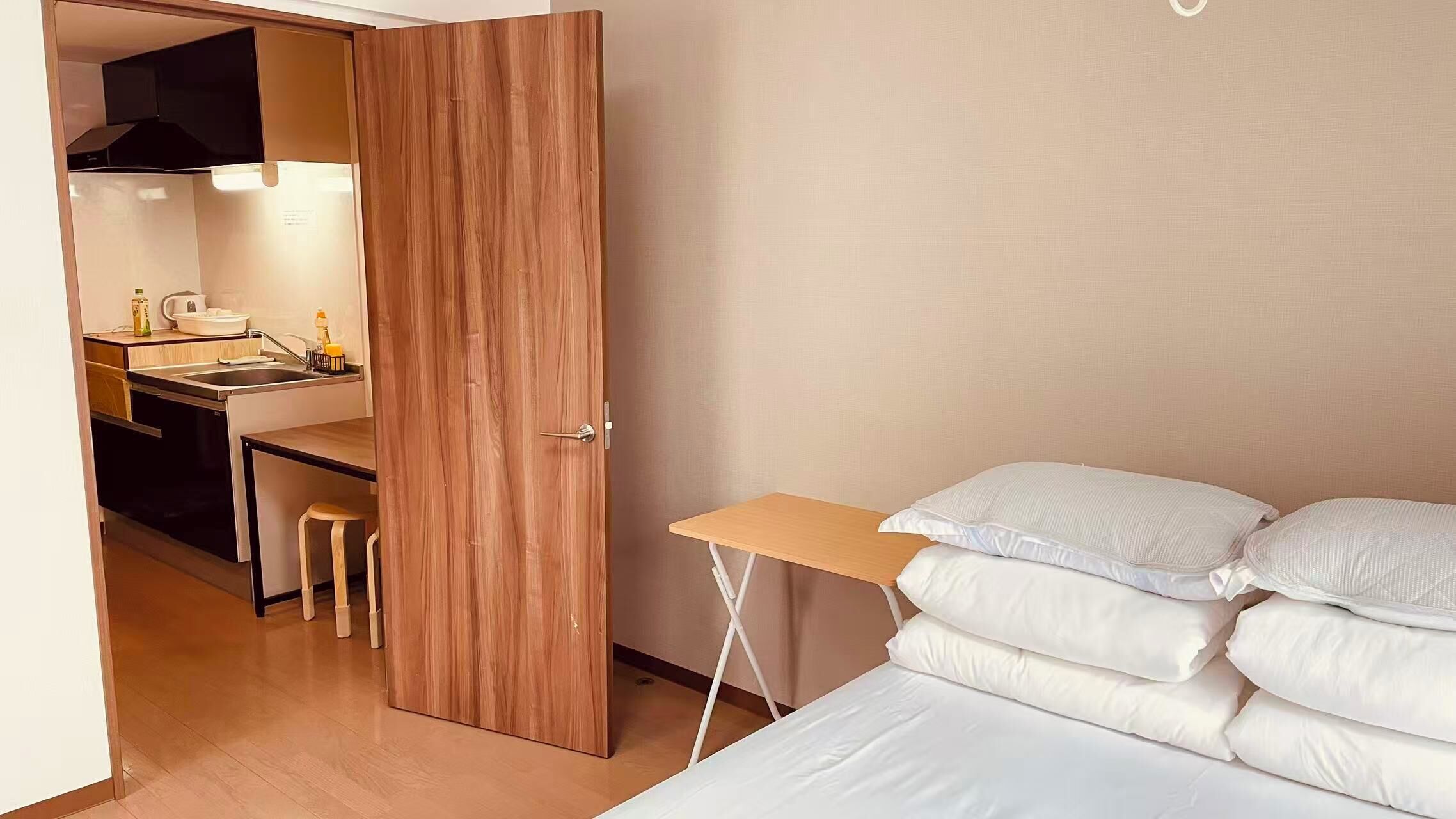 A bedroom with a bed, pillows, a desk, and a chair.