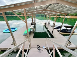 Eine überdachte Pier mit Billardtisch, einem grünen Luftboot und einem Kajak.