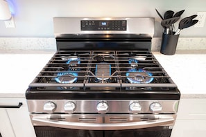 A stainless steel gas range with four burners and a digital control panel. - Secluded Luxe Lake House, Fire Pit, Hot Tub, Sauna, Private Dock (Bryson City)