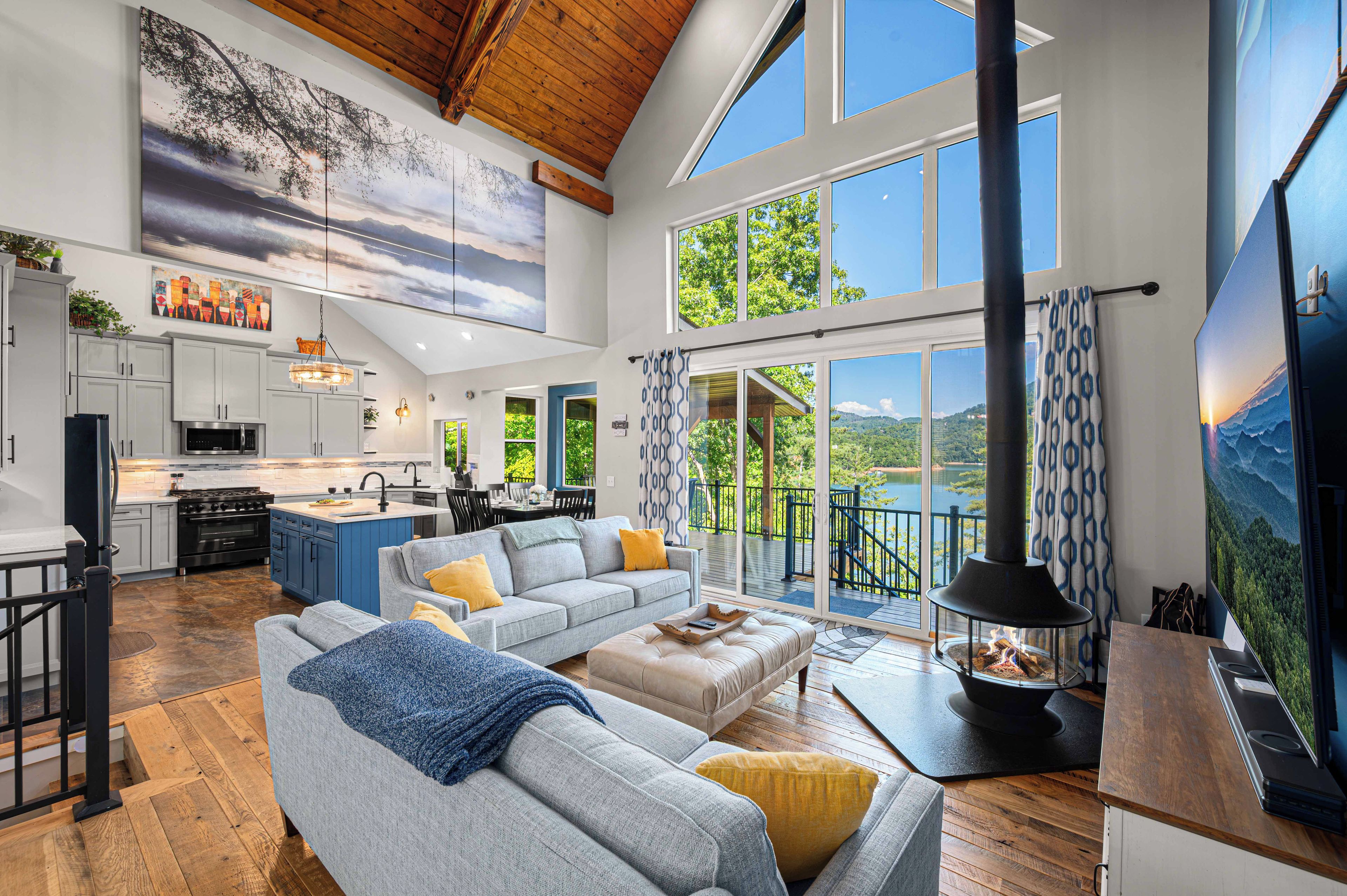 A spacious living area with a large sofa, a fireplace, and a view of a lake.