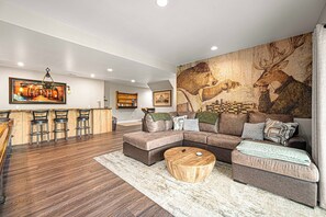 A modern living room with a sectional sofa, a coffee table, and a bar area with stools. - Secluded Luxe Lake House, Fire Pit, Hot Tub, Sauna, Private Dock (Bryson City)