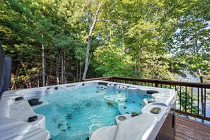 Un jacuzzi en una terraza de madera rodeada de árboles.