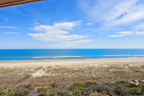 Blick auf einen Strand mit einer Holzpromenade, die zum Ufer führt.
