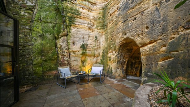 A stone-walled interior with two chairs and a table, suggesting a dining or meeting area.