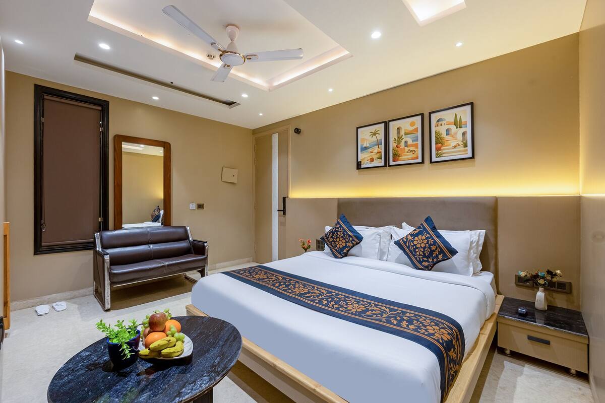 A hotel room with a bed, a seating area, a ceiling fan, and artwork on the wall.