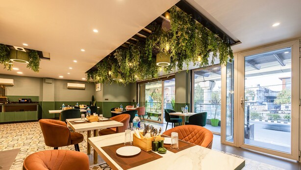 A restaurant with indoor seating, a bar area, and large windows offering a view of the street. - Fabhotel Lee Way (New Delhi)