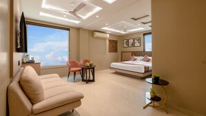 A modern bedroom with a sofa, a bed, a small table, and a TV mounted on the wall. - Fabhotel Lee Way (New Delhi)