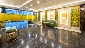 A modern lobby with a green sofa, a round table, and framed artwork on the walls. - Fabhotel Lee Way (New Delhi)