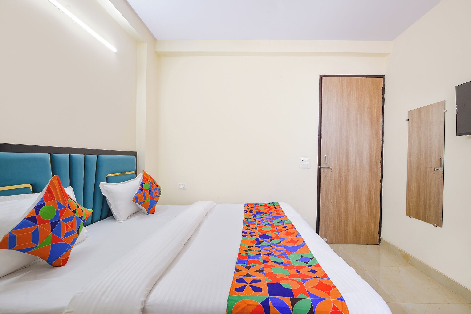 Una habitación de hotel con una cama, una puerta de madera y un armario.