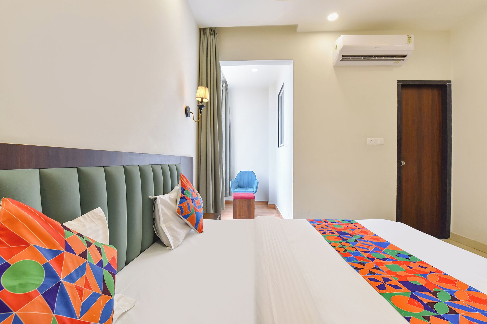Habitación de hotel con cama, una silla, una puerta y un equipo de aire acondicionado.