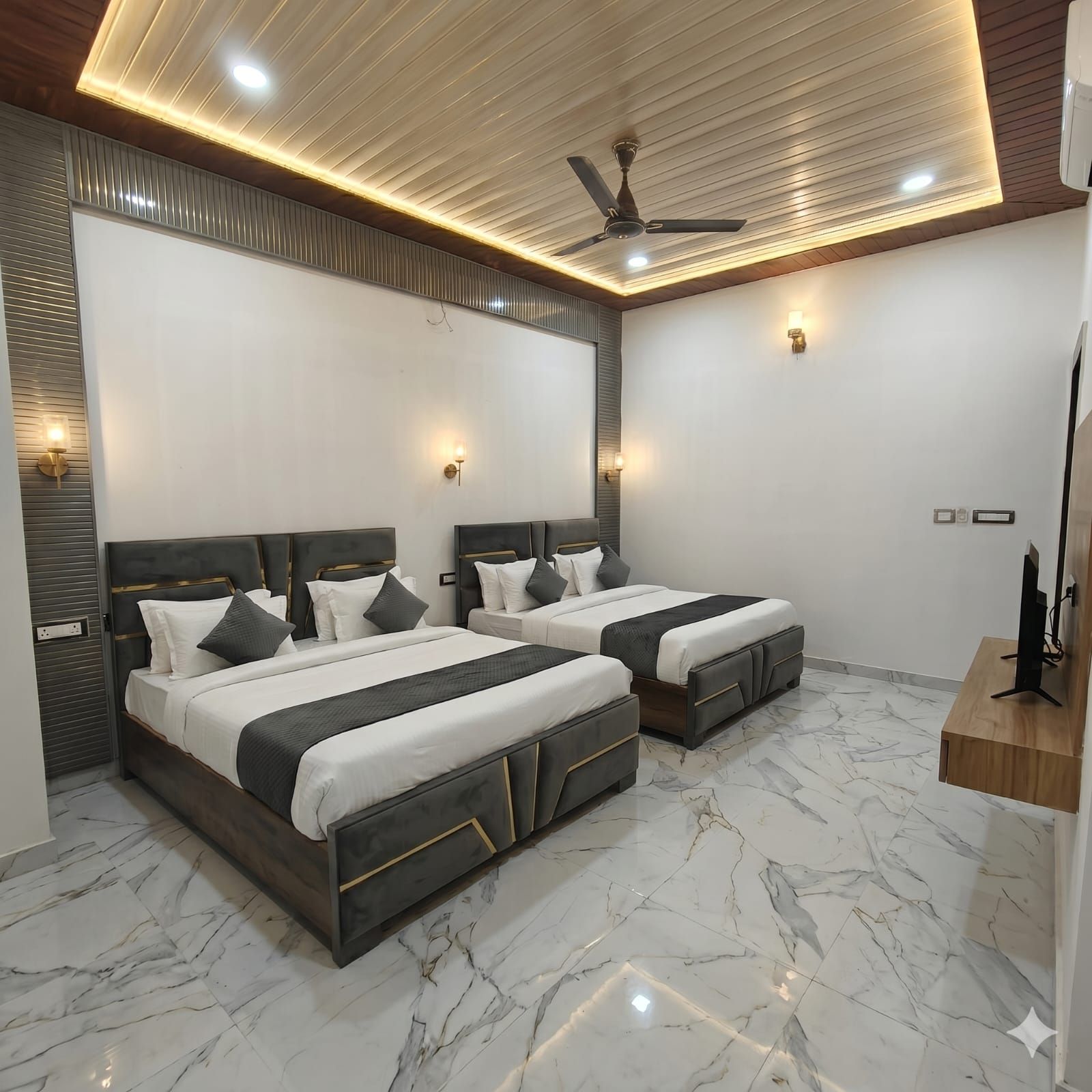 Habitación de hotel con dos camas, ventilador de techo y suelo de mármol.