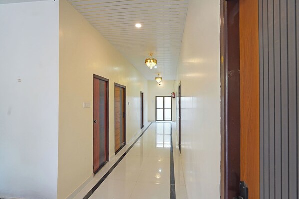 A hallway with doors, a chandelier, and a fire alarm. - Via The Sarnath Residency (Varanasi)