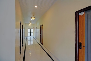 A hallway with a chandelier, doors, and a fire extinguisher. - Via The Sarnath Residency (Varanasi)