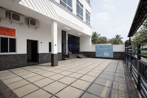 A hotel entrance with a tiled courtyard, a black gate, and a signboard.