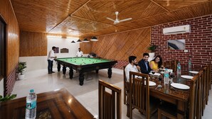 A billiards room with a pool table, wooden ceiling, and brick walls. - FabHotel Expressway 135 - Near By KJR Hospital (Noida)